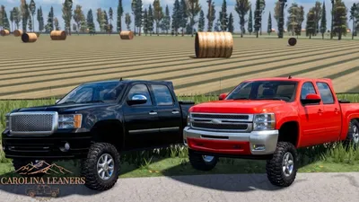 Black and red squatted trucks leaning back on a hay field