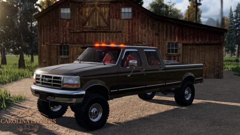 Green lifted Ford F-350 dually with off-road tires parked by a red barn